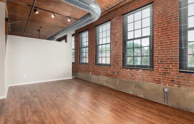 an empty living room with brick walls and wood floors