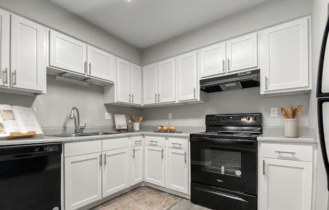 A kitchen with white cabinets and black appliances.
