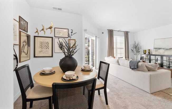 A dining room with a table set for two and a couch in the background.