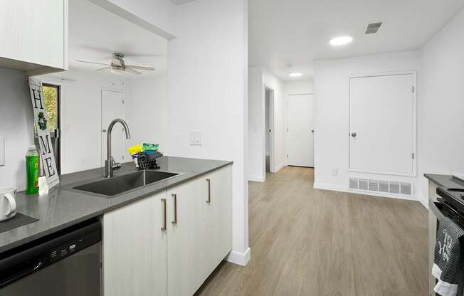 A kitchen with white cabinets and a black dishwasher.