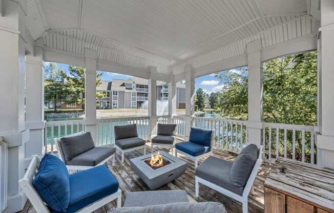 a covered porch with couches and chairs and a fire pit