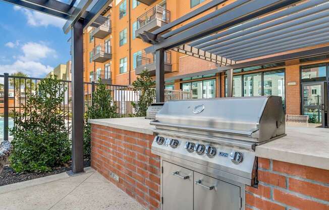 A stainless steel grill is on a brick wall.