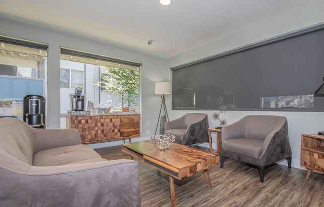 Inside the renovated leasing office at Foster Creek apartments with gray couches and chairs and a wooden coffee table