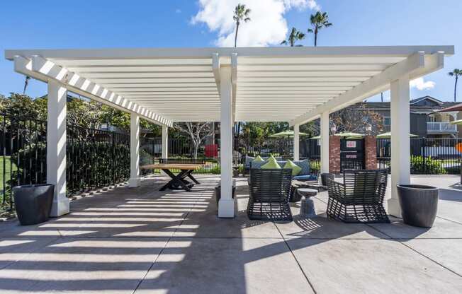 a covered patio with tables and chairs under a white roof