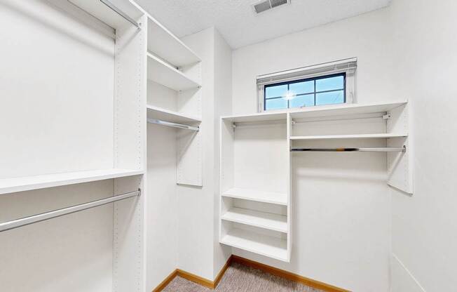 A white walk-in closet with shelves and a window.