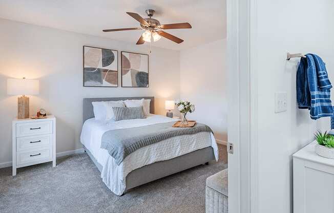 A bedroom with a bed, nightstand, and a ceiling fan.