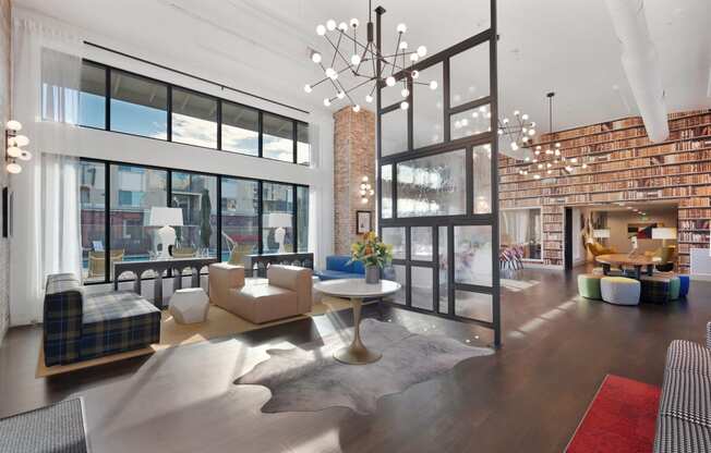 The Sierra Gateway Leasing office and clubhouse with couches a table and a chandelier right at the entrance.  There is funky & fun library book wallpaper on the back wall.