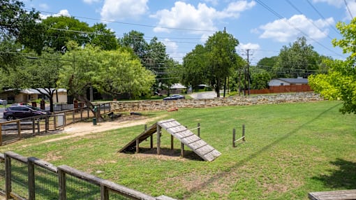 A park with a wooden slide and a fence.