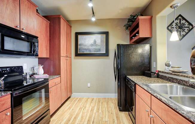 a kitchen with black appliances and wood cabinets At Metropolitan Apartments in Little Rock, AR