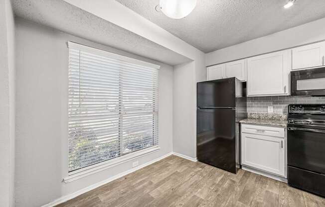 A kitchen with black appliances and white cabinets.
