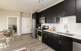A modern kitchen with black cabinets and stainless steel appliances.