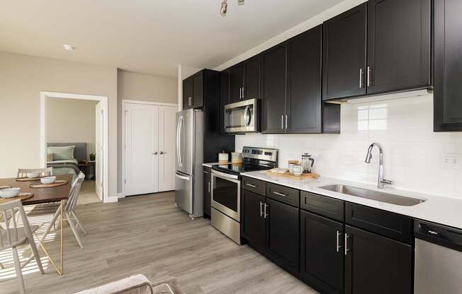 A modern kitchen with black cabinets and stainless steel appliances.