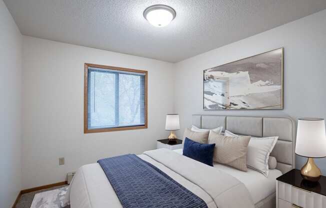 a bedroom with a large bed and a window. Fargo, ND Prairie Park Apartments