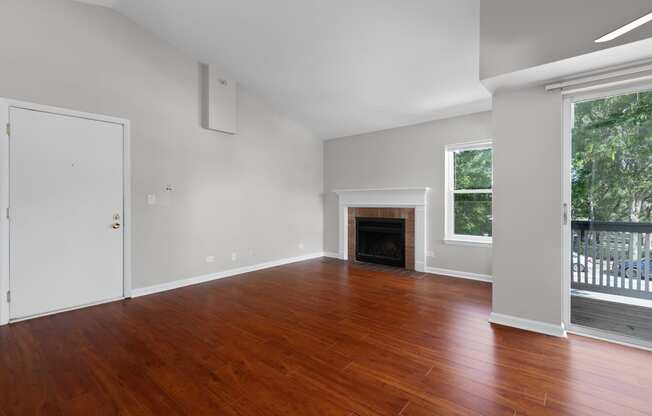 an empty living room with wood floors and a fireplace