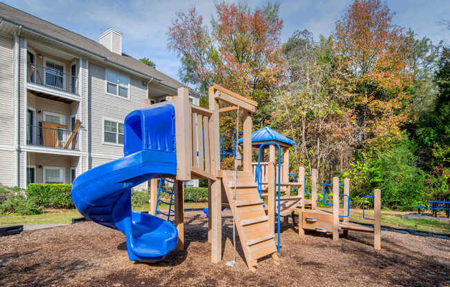 A playground with a blue slide and wooden structure.