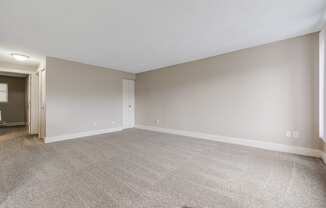 A large, empty room with carpeted flooring and white walls.