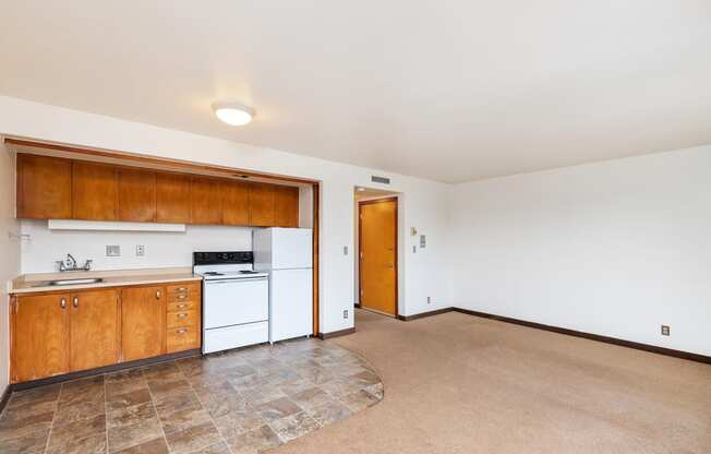 the living room and kitchen of an empty house with white appliances and wooden cabinets