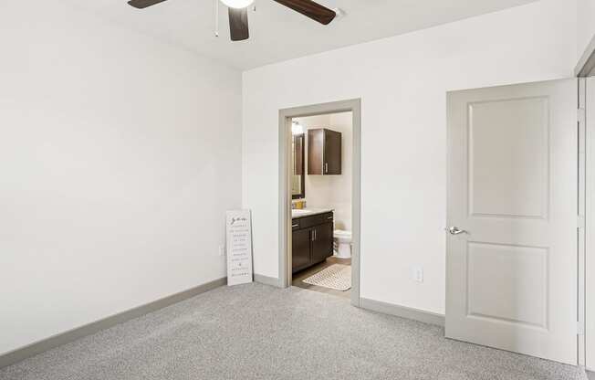 A bedroom with white walls, a closet, and a fan on the ceiling at GreenVue Apartments in Richardson, TX