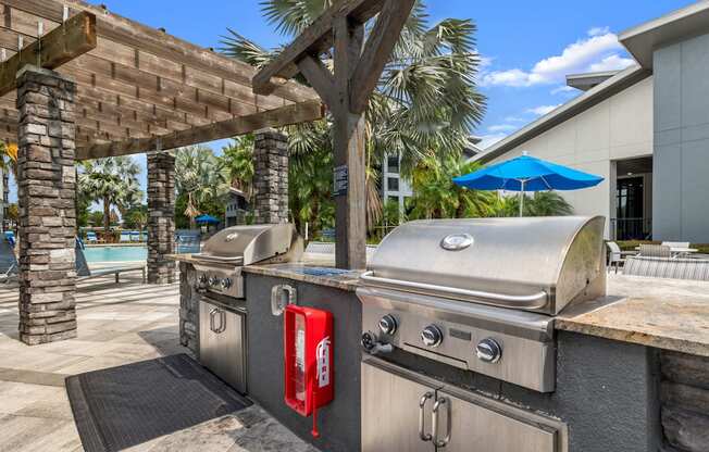 a backyard with two stainless steel barbecue grills and a picnic table