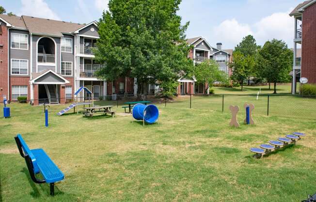 a large grassy area with a playground and picnic tables in front of an apartment complex at Lincoln at Wolfchase, Cordova