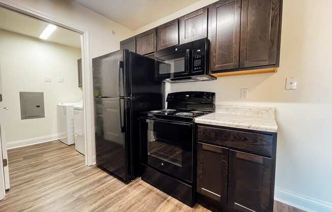 a kitchen with black appliances and wood flooring in a home