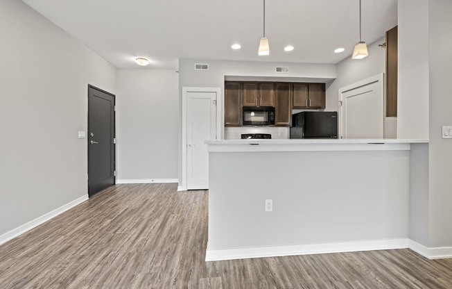 an kitchen and living room with a counter top and a refrigerator and a microwave