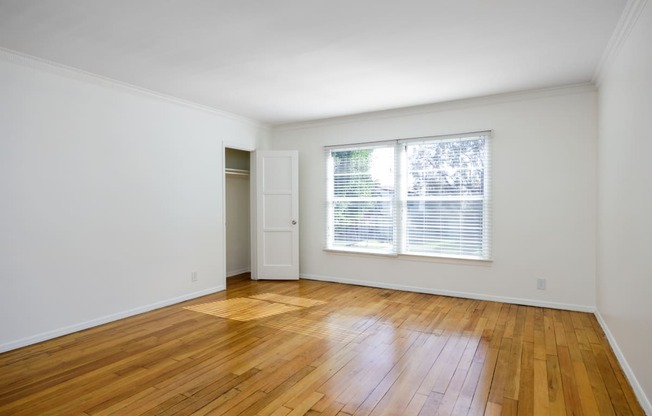 an empty living room with wood floors and a window