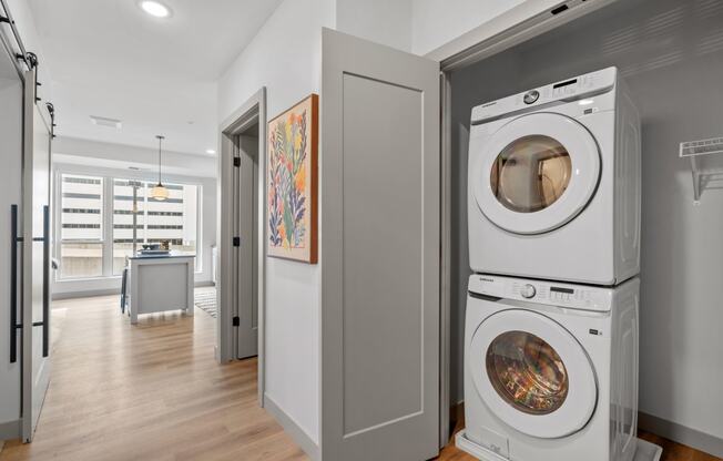 a washer and dryer in a living room with a door to a kitchen at The Mera, St Louis Park, Minnesota