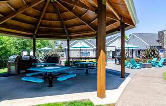a picnic pavilion with benches and picnic tables in a park