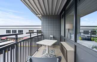 A balcony with a table and chairs overlooking a cityscape.