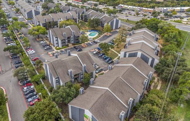 an aerial view of several buildings with cars parked in a parking lot