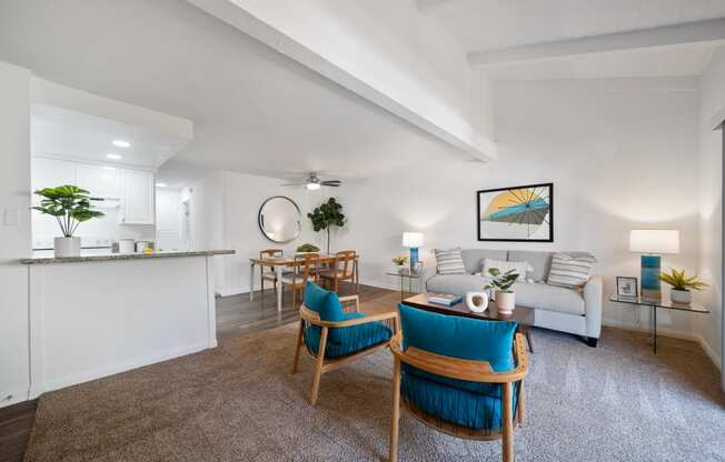 a living room with white walls and a white couch with blue chairs