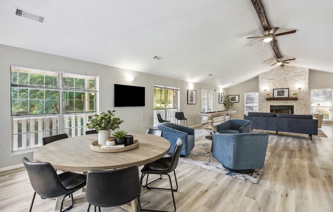 A modern living room with a round table and chairs, a flat screen TV, and a fireplace.