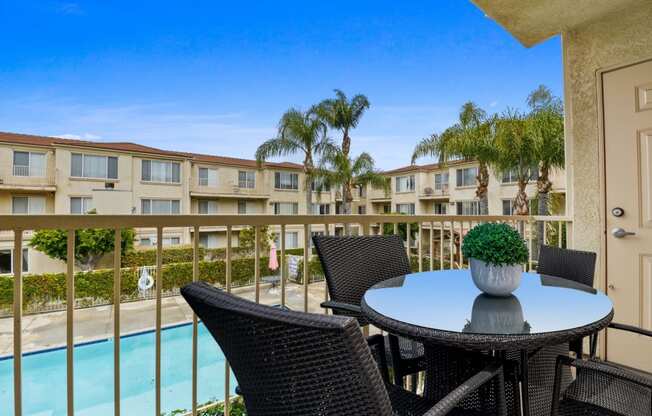 a patio with a table and chairs and a pool in the background