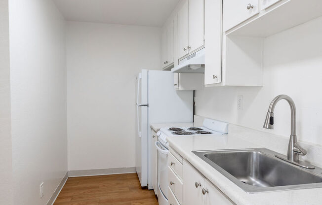 a kitchen with white cabinets and a stainless steel sink