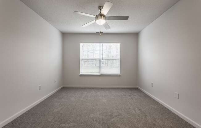 an empty room with a ceiling fan and a window