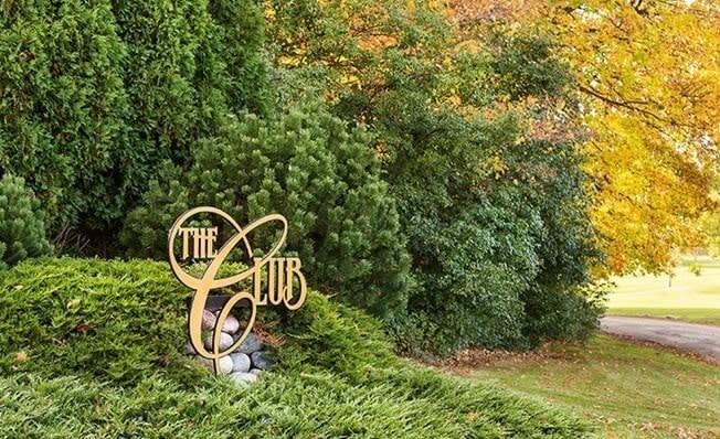 a sign in a grassy area with trees in the background