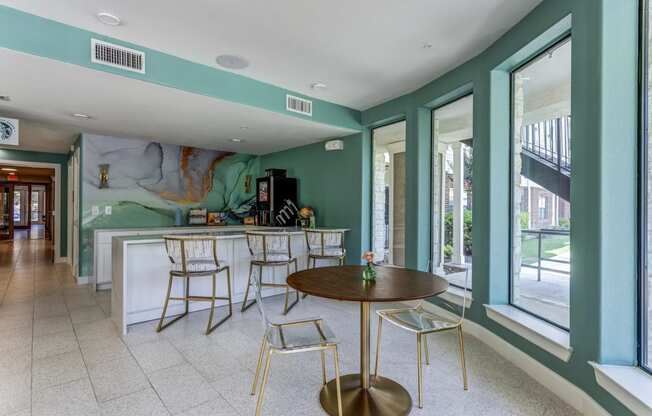 a room with a table and chairs in front of a window with a mural on the wall