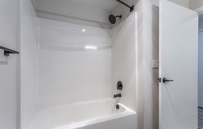 a bathroom with a white bathtub and a shower with a black shower head