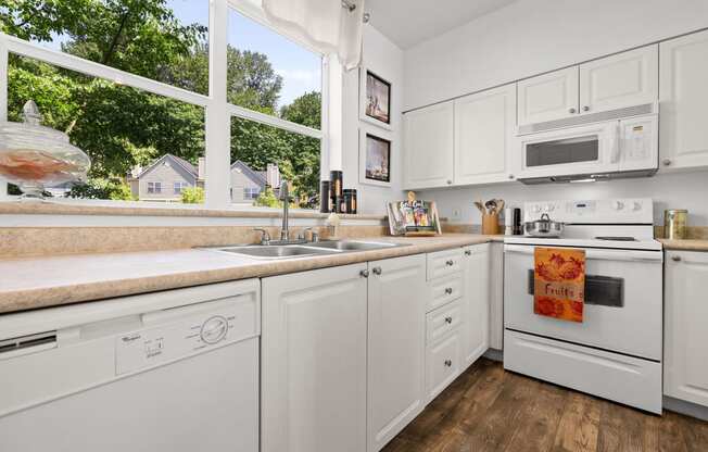 a kitchen with white cabinets and a large window