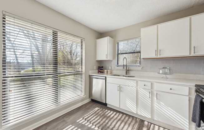 A kitchen with white cabinets and a striped rug on the floor.