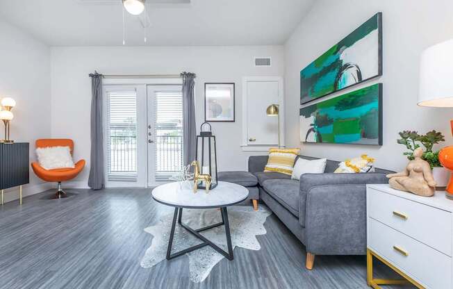 A living room with a grey couch, a white coffee table, and a painting on the wall.
