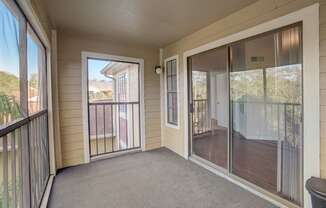 a covered porch with glass sliding doors and a balcony