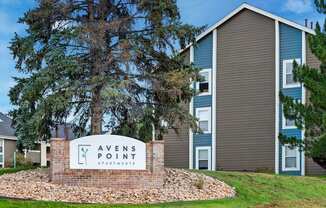 A sign that says "Avens Point Apartments" in front of a building.