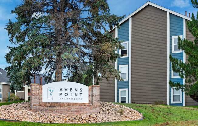 A sign that says "Avens Point Apartments" in front of a building.