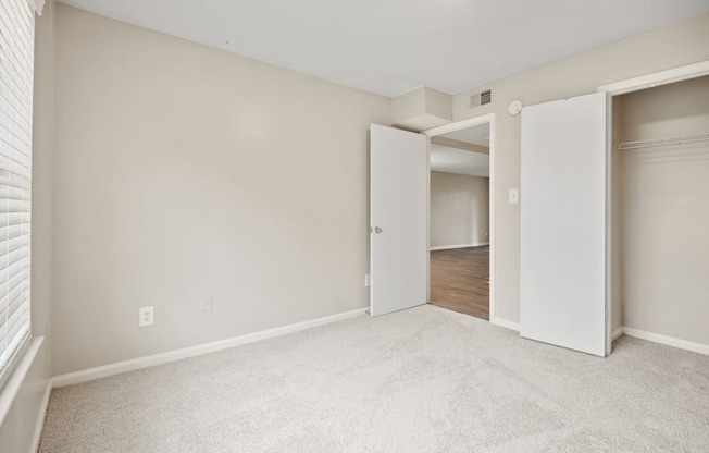 A room with white walls and carpeted floor with two open doors.