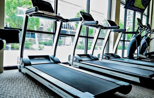 two treadmills in a gym with a large window