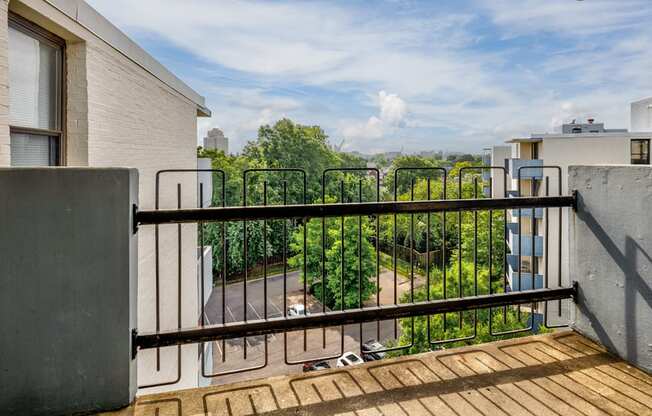 the balcony has a view of the trees and the city in the distance