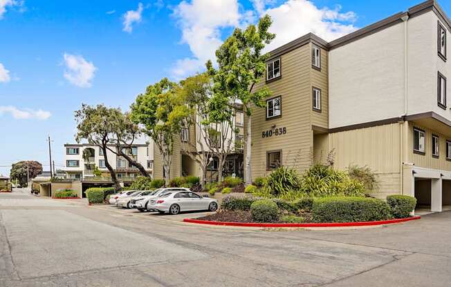 a street view of an apartment building with cars parked in front
