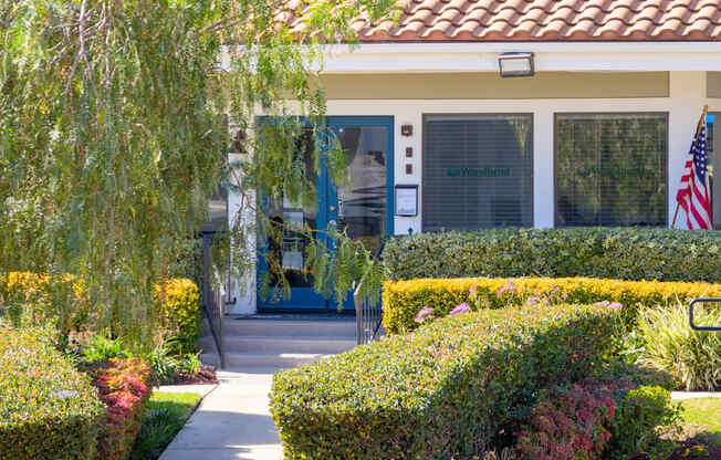 A building with a sign that says Woodend is surrounded by bushes and trees.